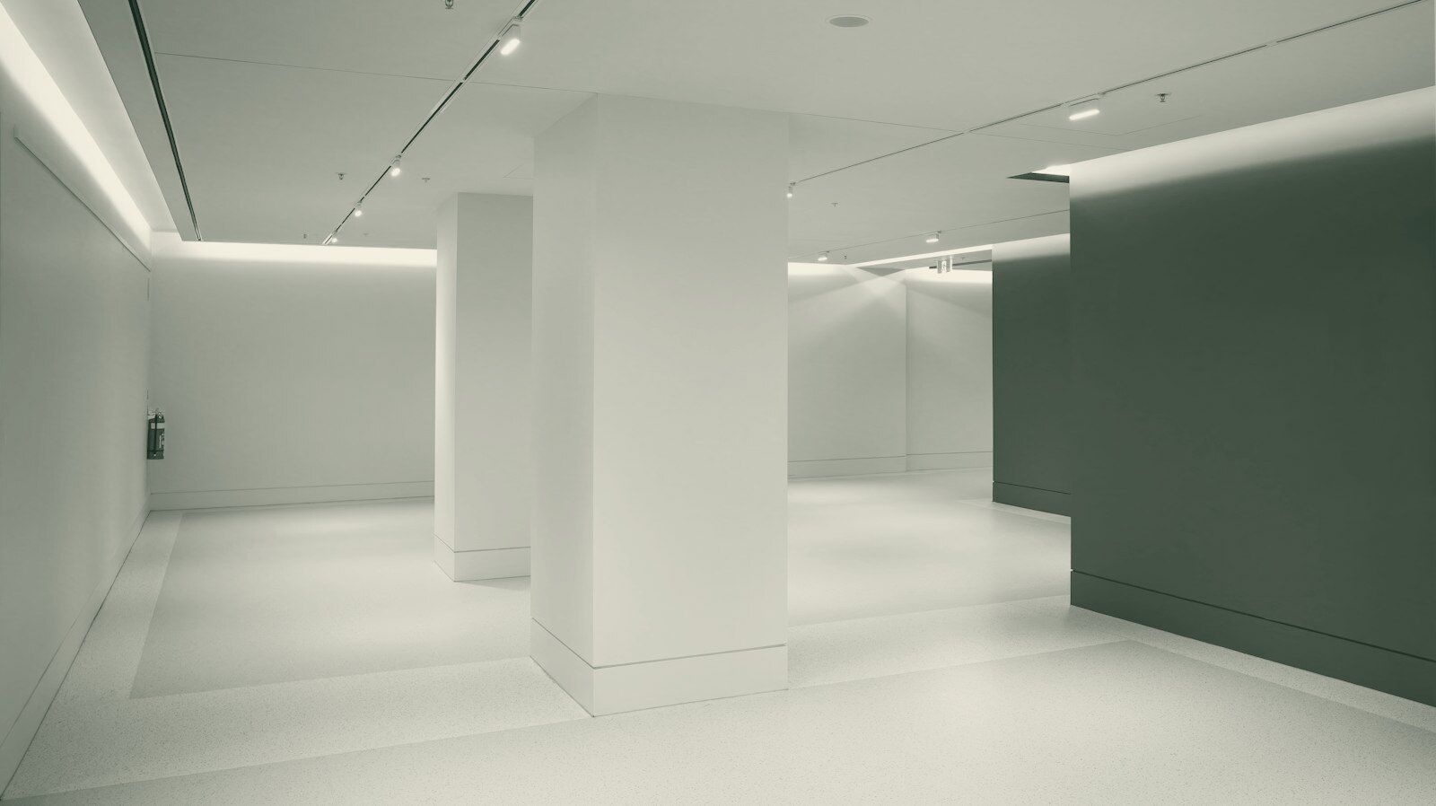 A minimalist interior with white walls, a large pillar, and an orange accent wall