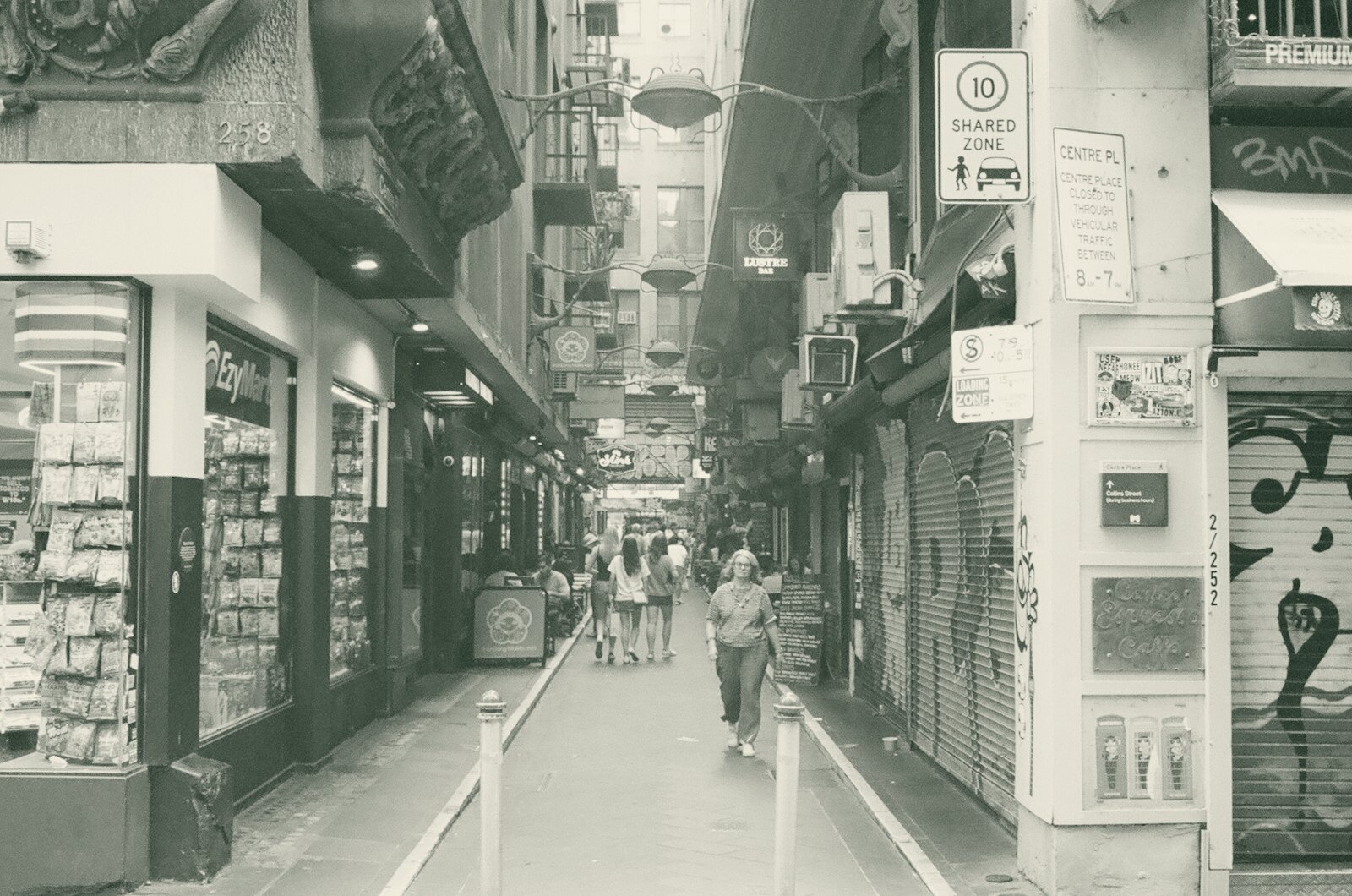 People walking down a narrow city alleyway with shops