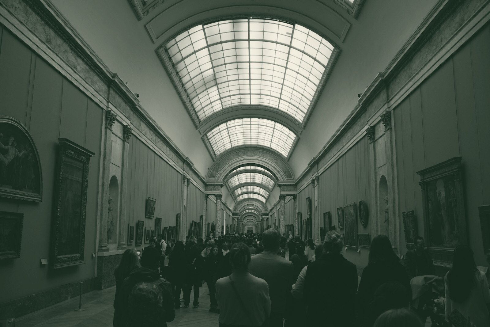 People walking through a long art gallery with paintings