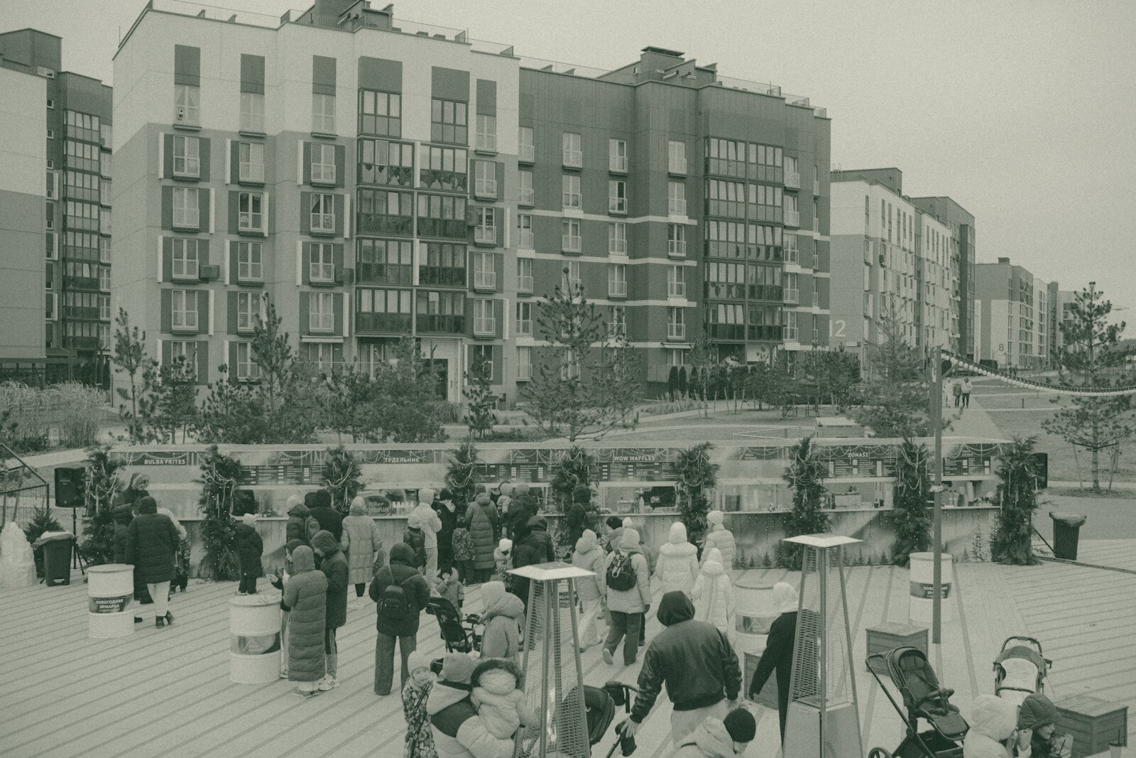 People gathered outside modern apartment buildings on a cloudy day