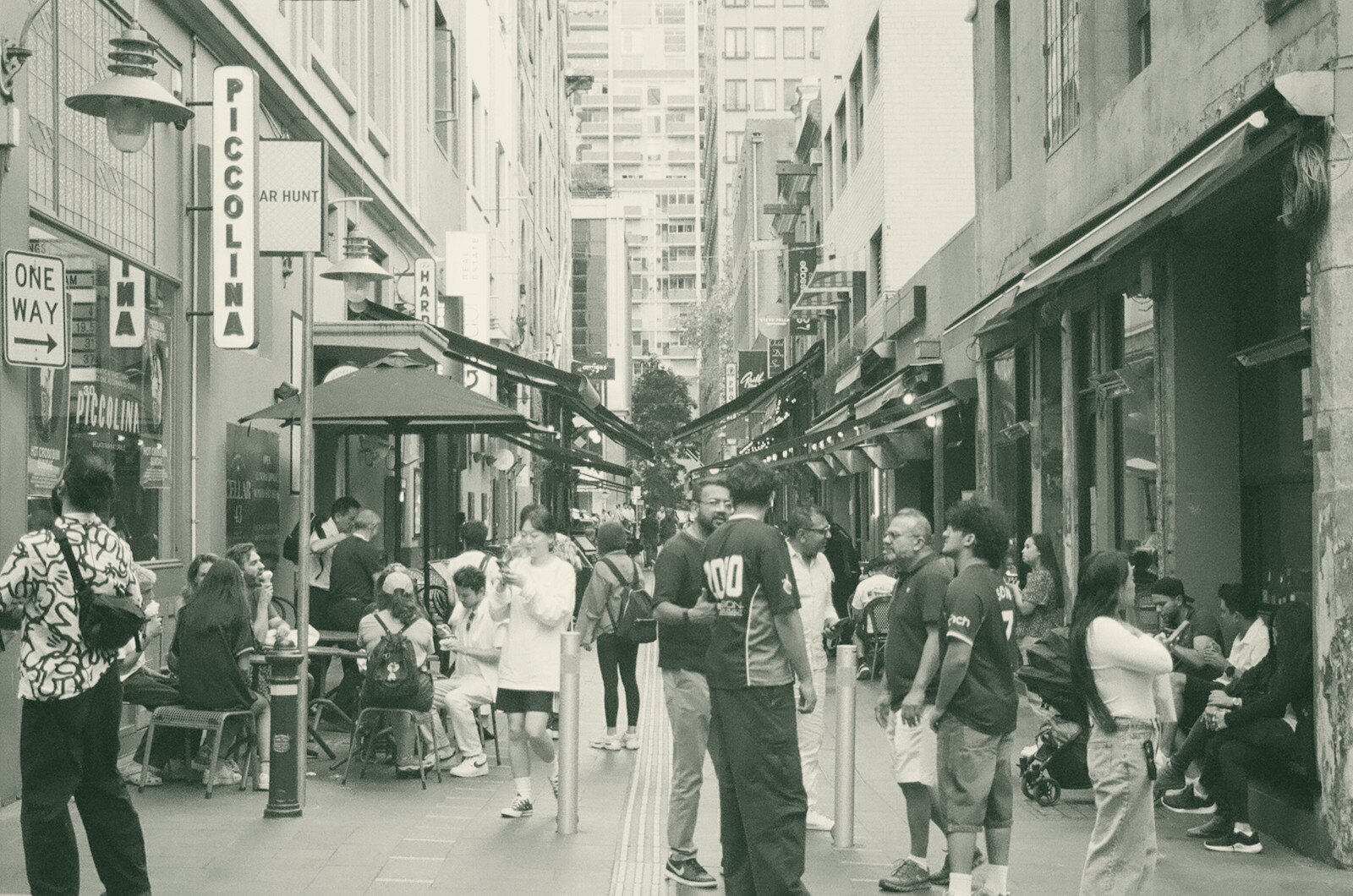 People gathered on a narrow city street with shops