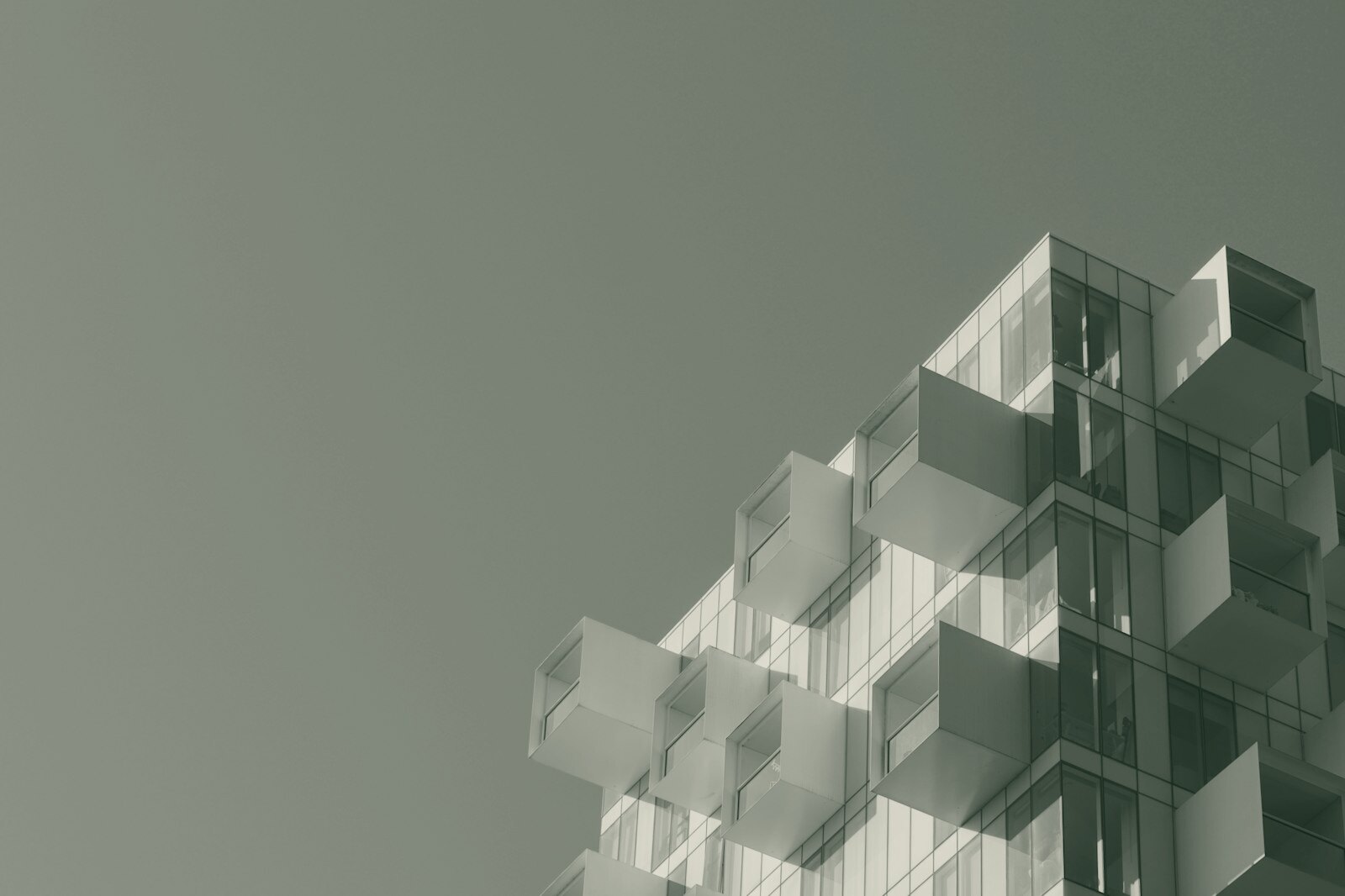 Modern building facade with protruding white balconies against a clear blue sky