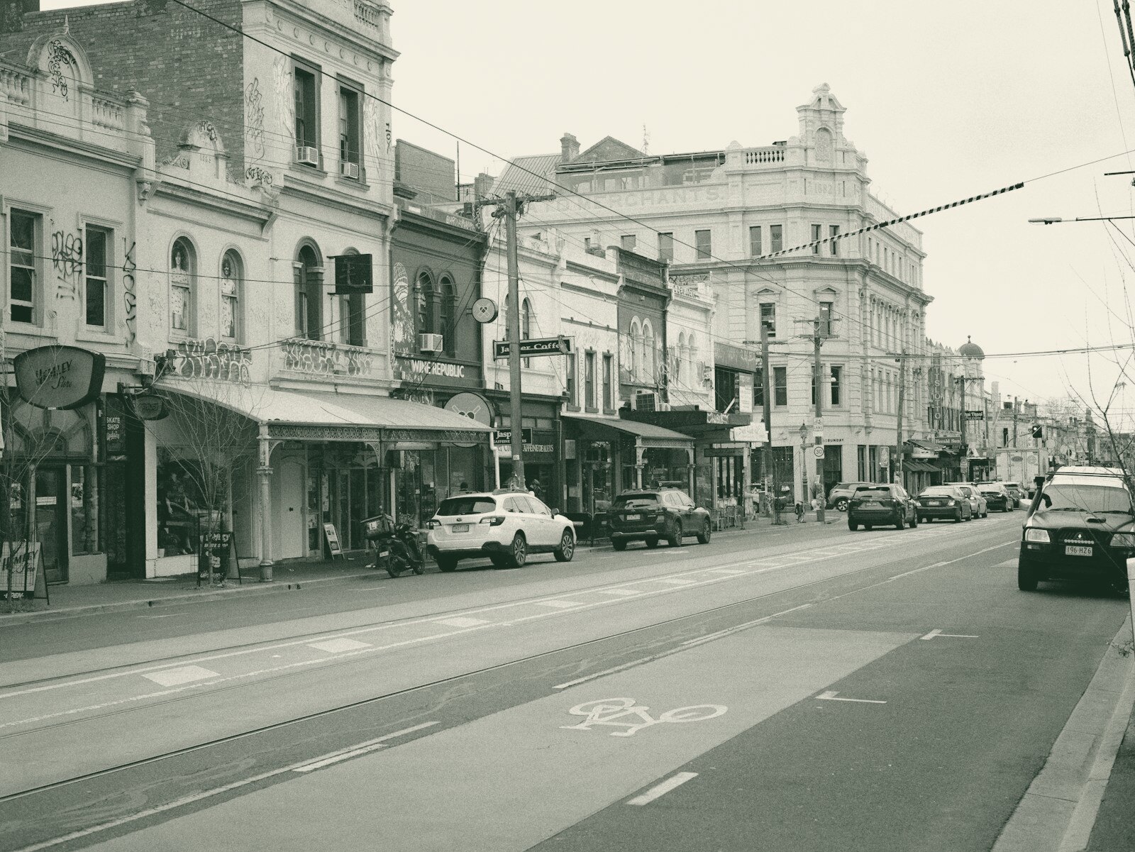 Historic street with shops, cars, and a green bike lane
