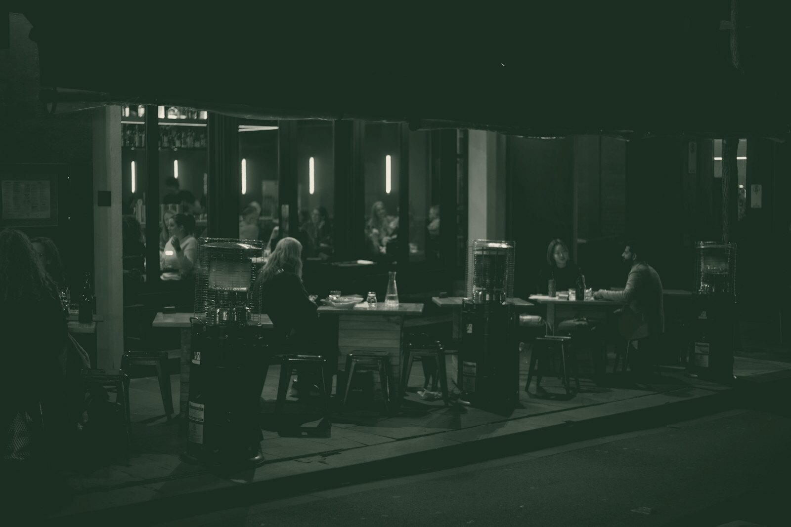 People dining at tables outside a restaurant at night